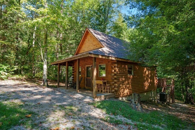 view of property exterior with cooling unit, roof with shingles, and log exterior