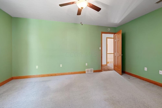 spare room featuring ceiling fan, carpet floors, visible vents, and baseboards