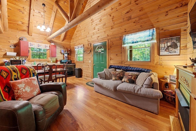 living room with wood walls, light hardwood / wood-style flooring, beamed ceiling, and an inviting chandelier