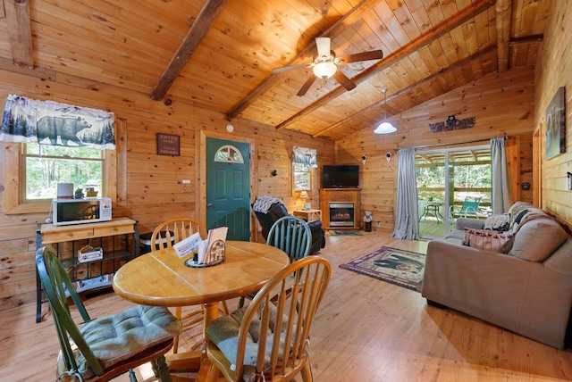 dining room featuring wooden walls, light hardwood / wood-style floors, and a healthy amount of sunlight