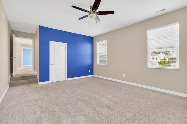 unfurnished bedroom featuring light colored carpet, multiple windows, and ceiling fan