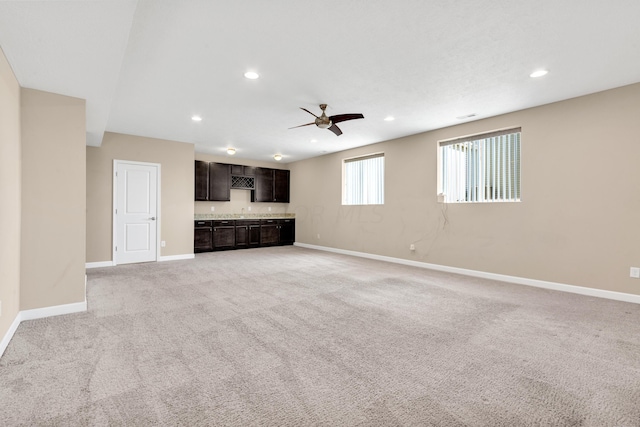 unfurnished living room featuring ceiling fan and light carpet