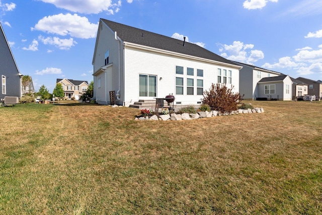 rear view of property featuring a lawn and central air condition unit