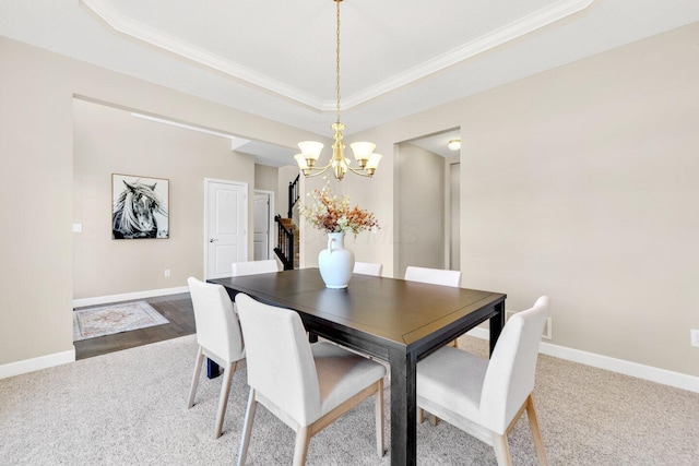 dining room featuring carpet, a raised ceiling, crown molding, and a notable chandelier