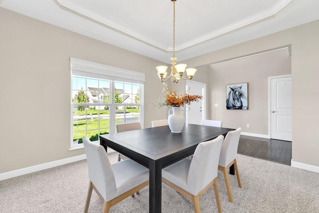 dining room featuring a tray ceiling, carpet floors, a notable chandelier, and ornamental molding