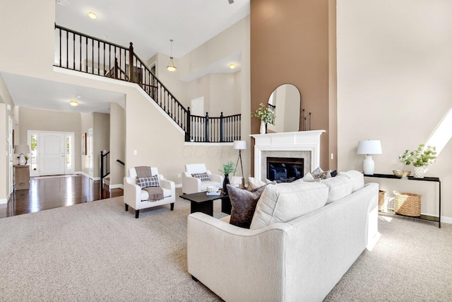 living room featuring a tile fireplace, a towering ceiling, and hardwood / wood-style flooring