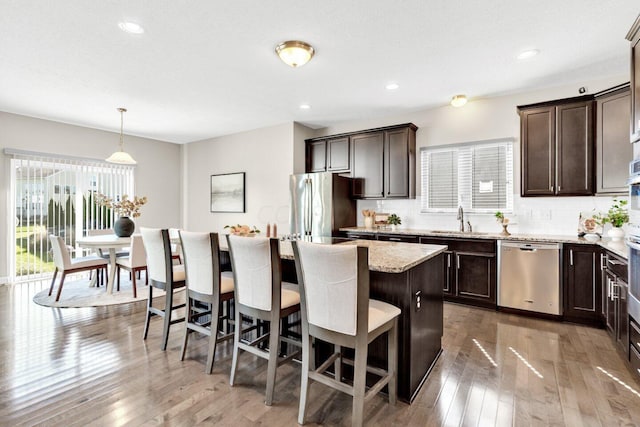 kitchen featuring hanging light fixtures, appliances with stainless steel finishes, a kitchen island, and a wealth of natural light