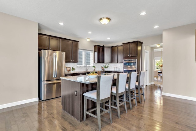 2353 Killdeer Pl, Galena, OH 43021 - kitchen with stainless steel appliances, dark brown cabinets, a kitchen island, wood finished floors, and recessed lighting