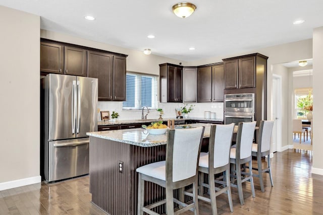 kitchen with hardwood / wood-style floors, plenty of natural light, a kitchen island, and stainless steel appliances