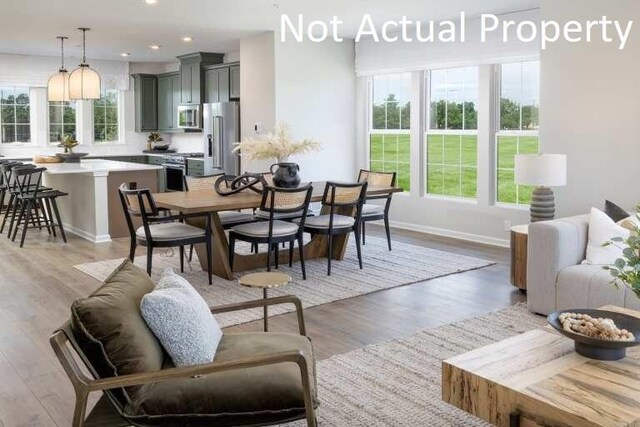 dining area featuring baseboards, light wood finished floors, recessed lighting, and a healthy amount of sunlight