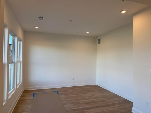 empty room featuring baseboards, visible vents, wood finished floors, and recessed lighting