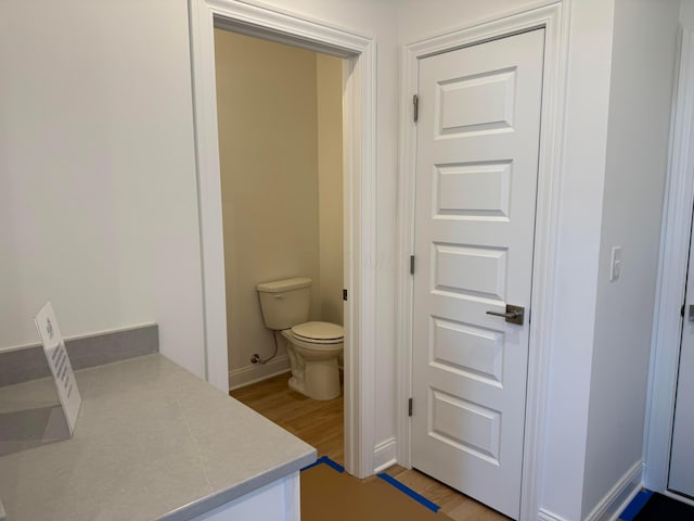 bathroom with baseboards, toilet, and wood finished floors