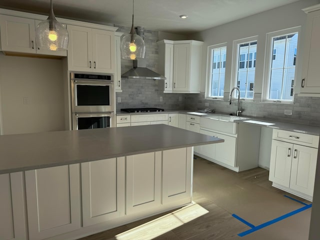 kitchen featuring stainless steel double oven, a sink, backsplash, and white cabinets