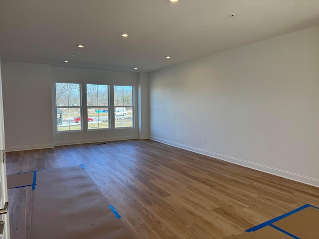 empty room featuring baseboards, wood finished floors, and recessed lighting