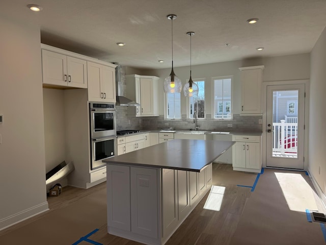 kitchen featuring stainless steel appliances, a center island, white cabinets, and wall chimney exhaust hood