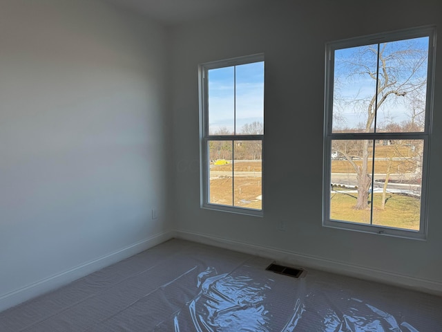 unfurnished room with visible vents, plenty of natural light, and baseboards