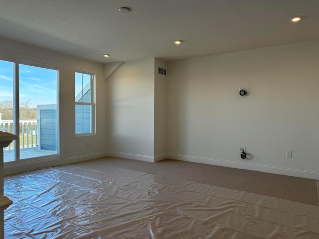 empty room featuring baseboards, visible vents, light colored carpet, a textured ceiling, and recessed lighting