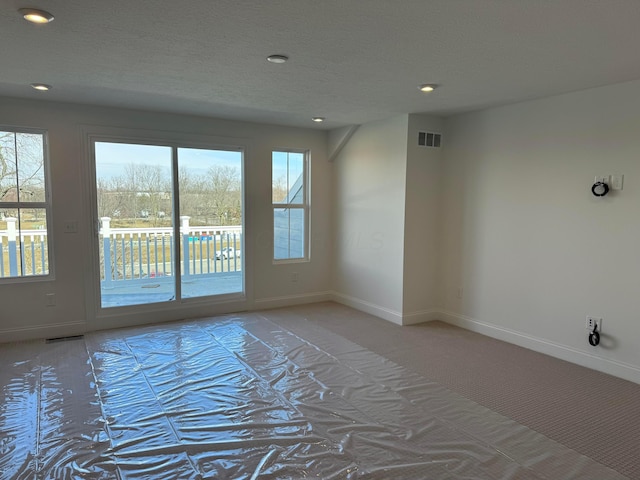 unfurnished room featuring a textured ceiling, visible vents, and baseboards