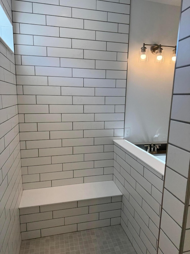 bathroom with a tile shower and a sink