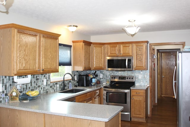 kitchen featuring sink, stainless steel appliances, tasteful backsplash, kitchen peninsula, and hardwood / wood-style flooring