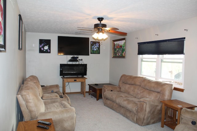 carpeted living room featuring ceiling fan and a textured ceiling