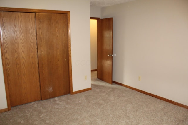 unfurnished bedroom featuring a closet and light colored carpet