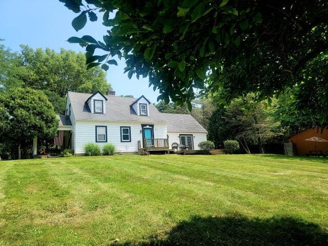 cape cod home featuring a deck and a front yard