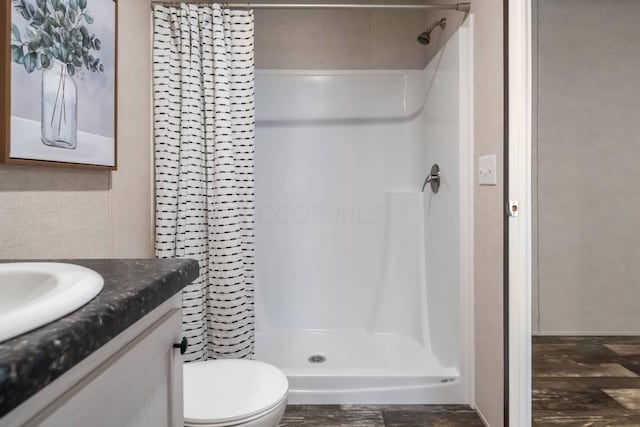 bathroom with curtained shower, vanity, wood-type flooring, and toilet