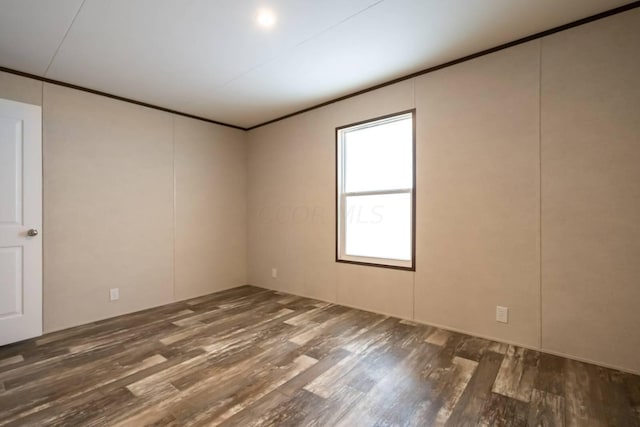 empty room with dark hardwood / wood-style flooring and ornamental molding