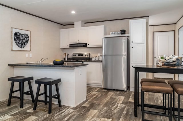 kitchen with dark hardwood / wood-style flooring, stainless steel appliances, white cabinetry, and a breakfast bar area