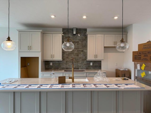 kitchen featuring tasteful backsplash, a center island with sink, hanging light fixtures, and sink