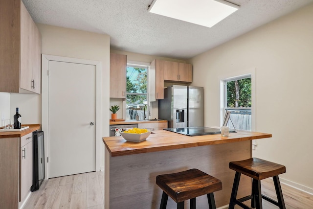 kitchen featuring a healthy amount of sunlight, a kitchen bar, butcher block counters, and appliances with stainless steel finishes