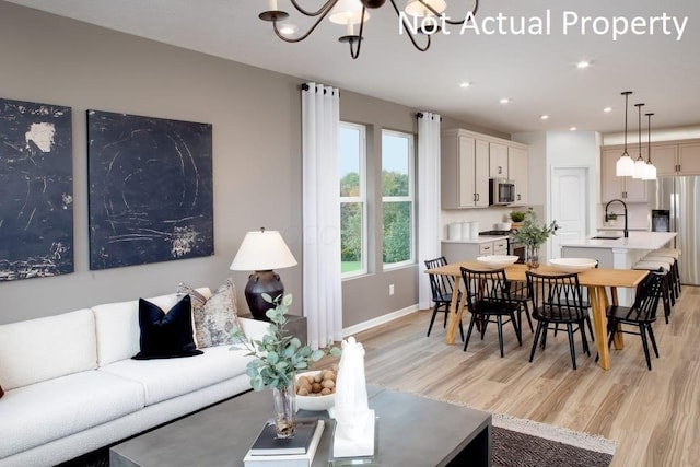 living room with light wood-type flooring, an inviting chandelier, and sink