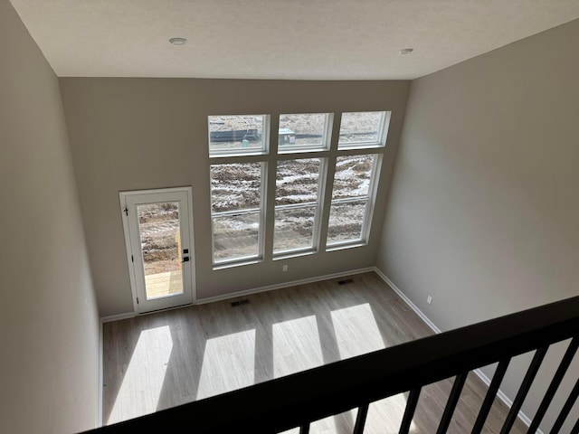 spare room with wood finished floors, visible vents, and baseboards