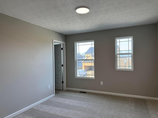 carpeted empty room featuring visible vents, baseboards, and a textured ceiling