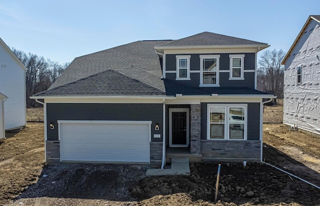 view of front facade featuring driveway, an attached garage, stone siding, and roof with shingles