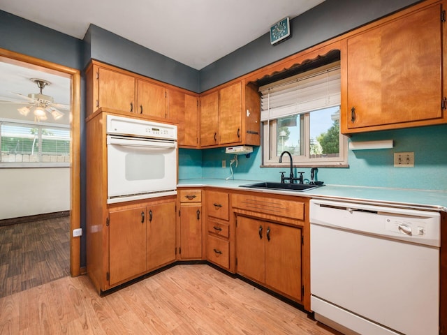 kitchen with white appliances, light hardwood / wood-style floors, ceiling fan, and sink