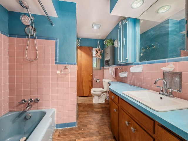 bathroom featuring vanity, hardwood / wood-style flooring, toilet, and tile walls