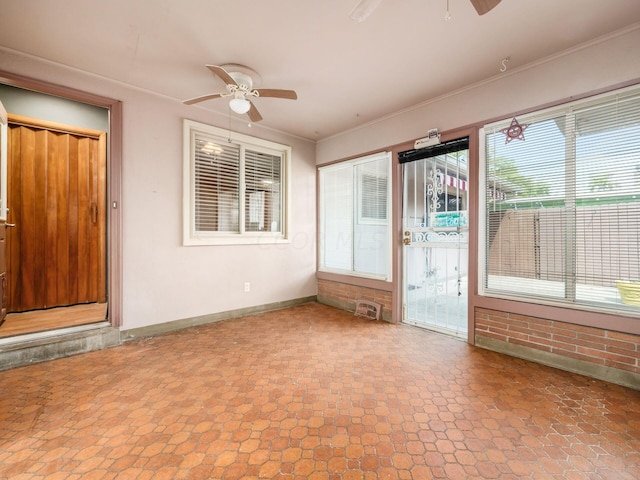 unfurnished sunroom featuring ceiling fan