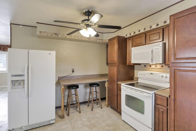 kitchen featuring ceiling fan, white appliances, and a breakfast bar area