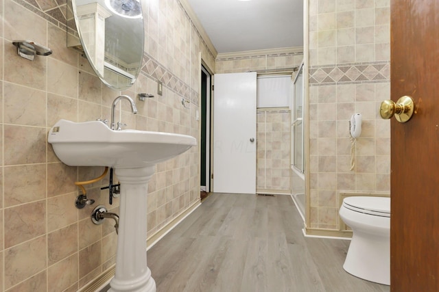 bathroom with hardwood / wood-style floors, toilet, tile walls, and walk in shower