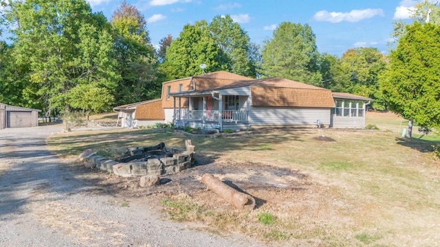 ranch-style home with a porch, a fire pit, a garage, and an outdoor structure