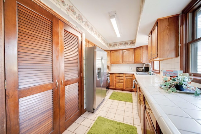 kitchen with tile countertops, sink, stainless steel appliances, and plenty of natural light