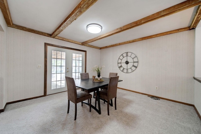 dining room with beam ceiling, light colored carpet, and french doors