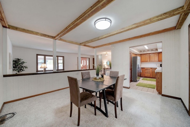 dining area featuring beam ceiling and light colored carpet