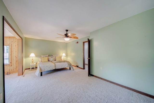 carpeted bedroom featuring ceiling fan and wooden walls