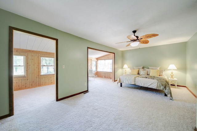 bedroom with light colored carpet, multiple windows, wooden walls, and ceiling fan