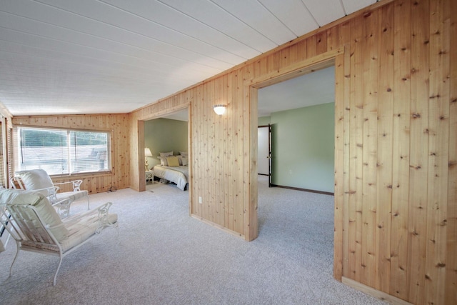 unfurnished room featuring wood walls, light colored carpet, and vaulted ceiling