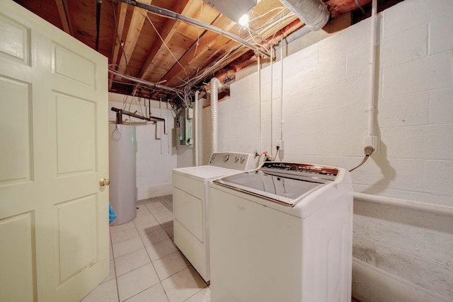 washroom featuring water heater, washer and clothes dryer, and light tile patterned floors