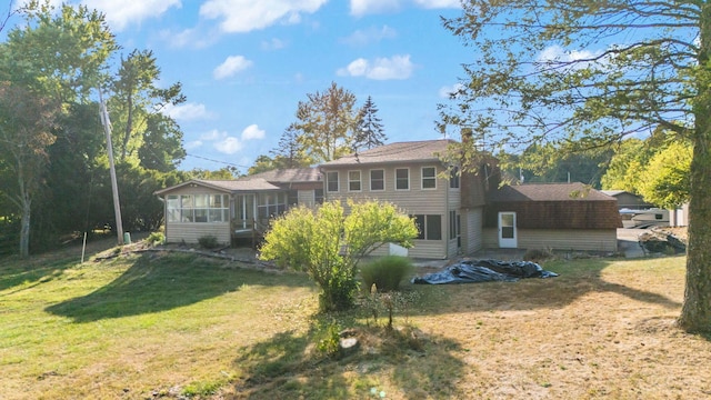 back of property with a sunroom and a yard